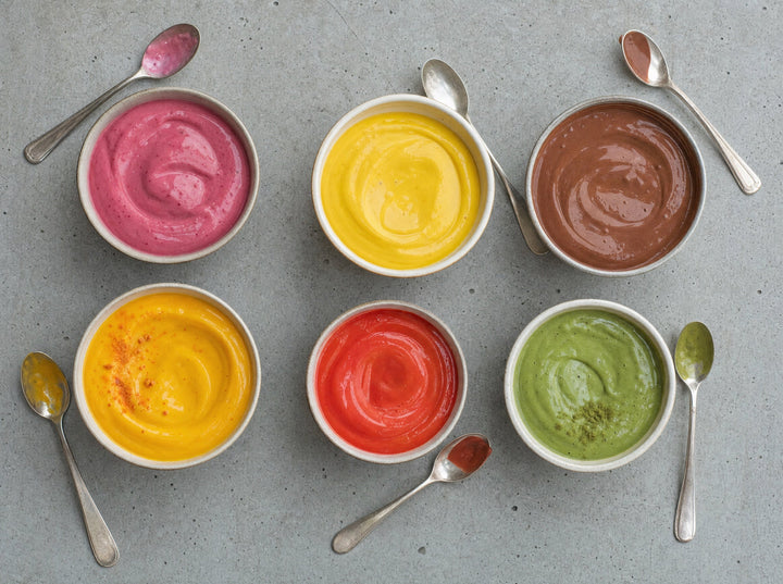 Sechs Schälchen Naturjoghurt, jedes mit einer anderen Sorte eingerührt