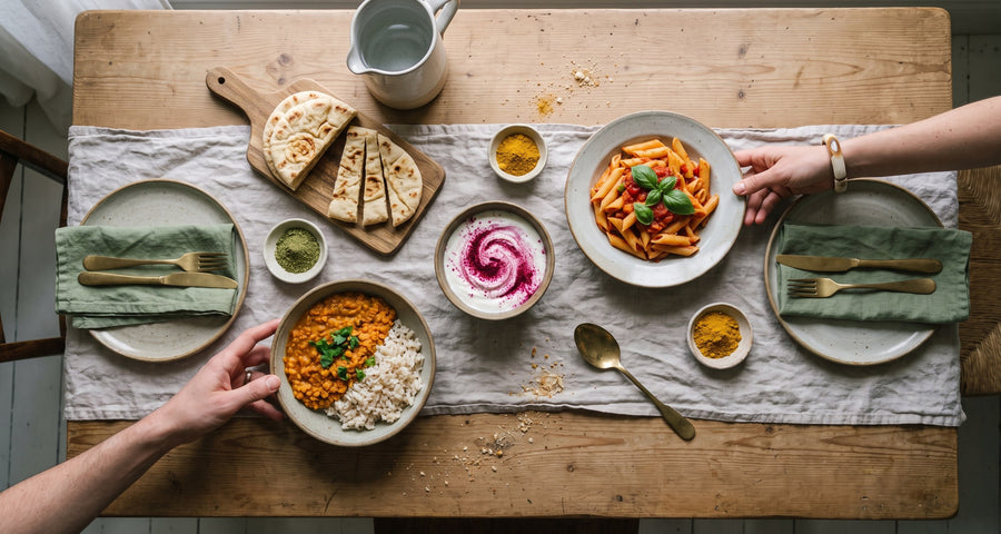 Familientisch von oben mit Dal, Pasta, Joghurt und Fladenbrot